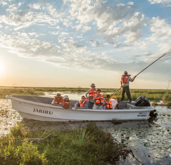 Lancha Jabirú con visitantes al atardecer sobre el estero