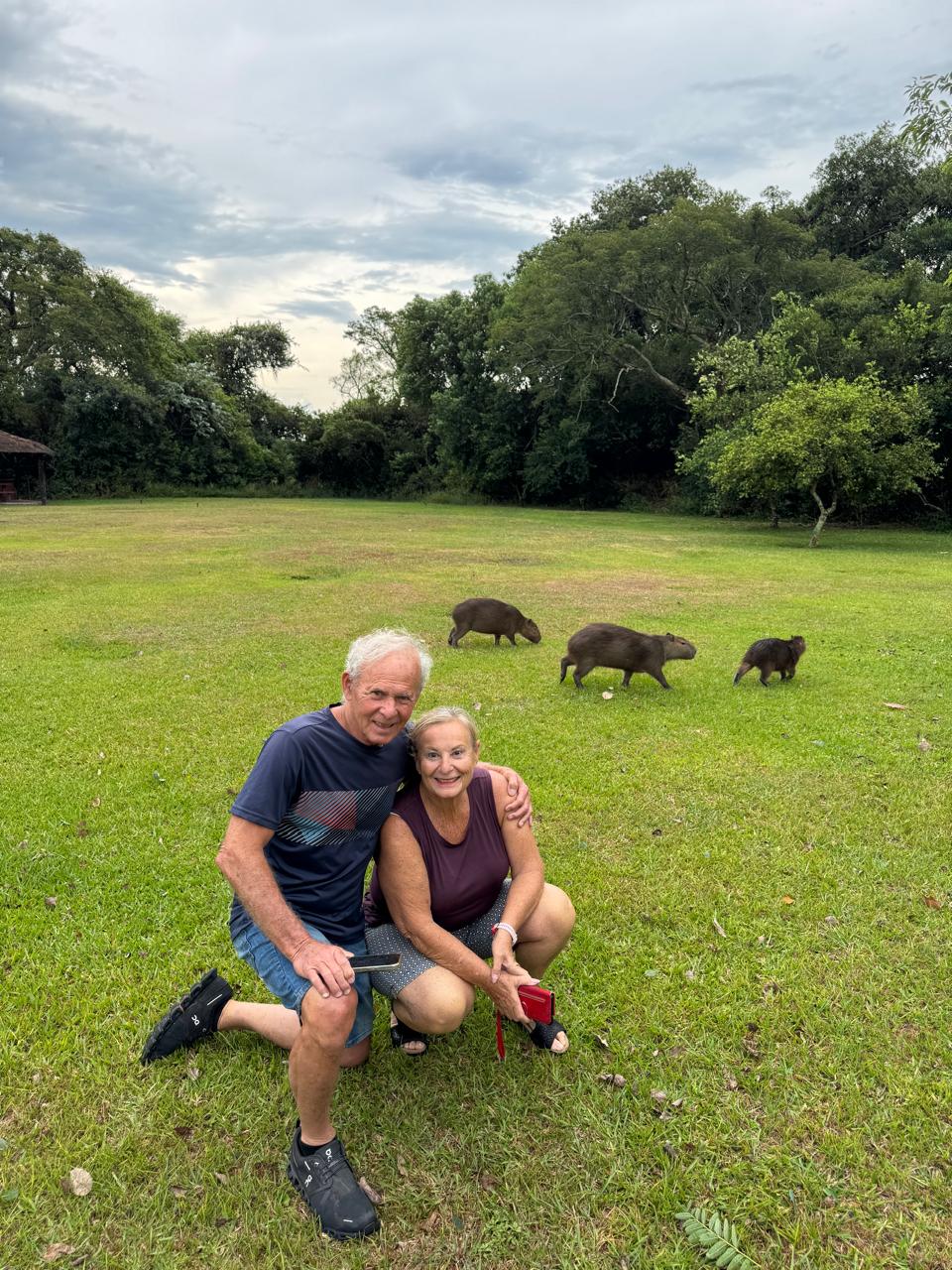 Visitantes sentados en el pasto, con carpinchos atrás