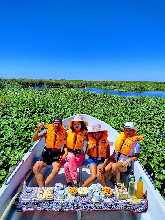 Merienda a bordo: familia con mate y chipá rodeada de plantas acuáticas