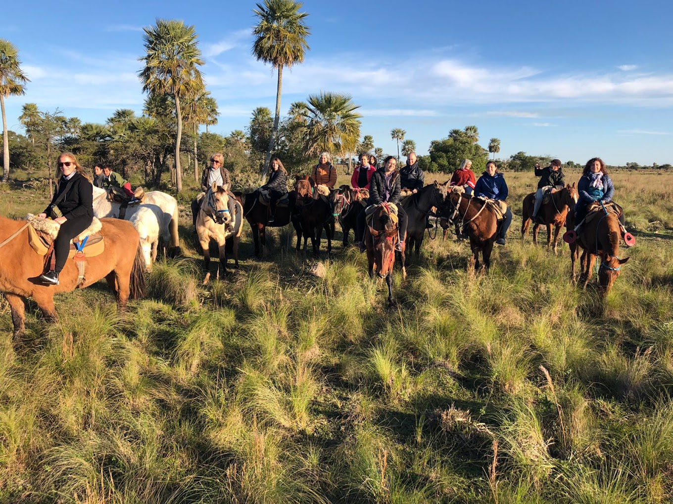 Jinetes atravesando los pastizales del Portal Laguna Iberá al atardecer