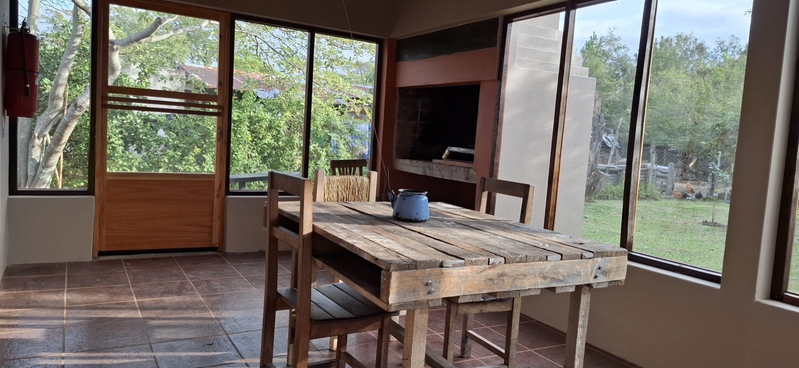 El quincho con parrilla y ventanales al jardín