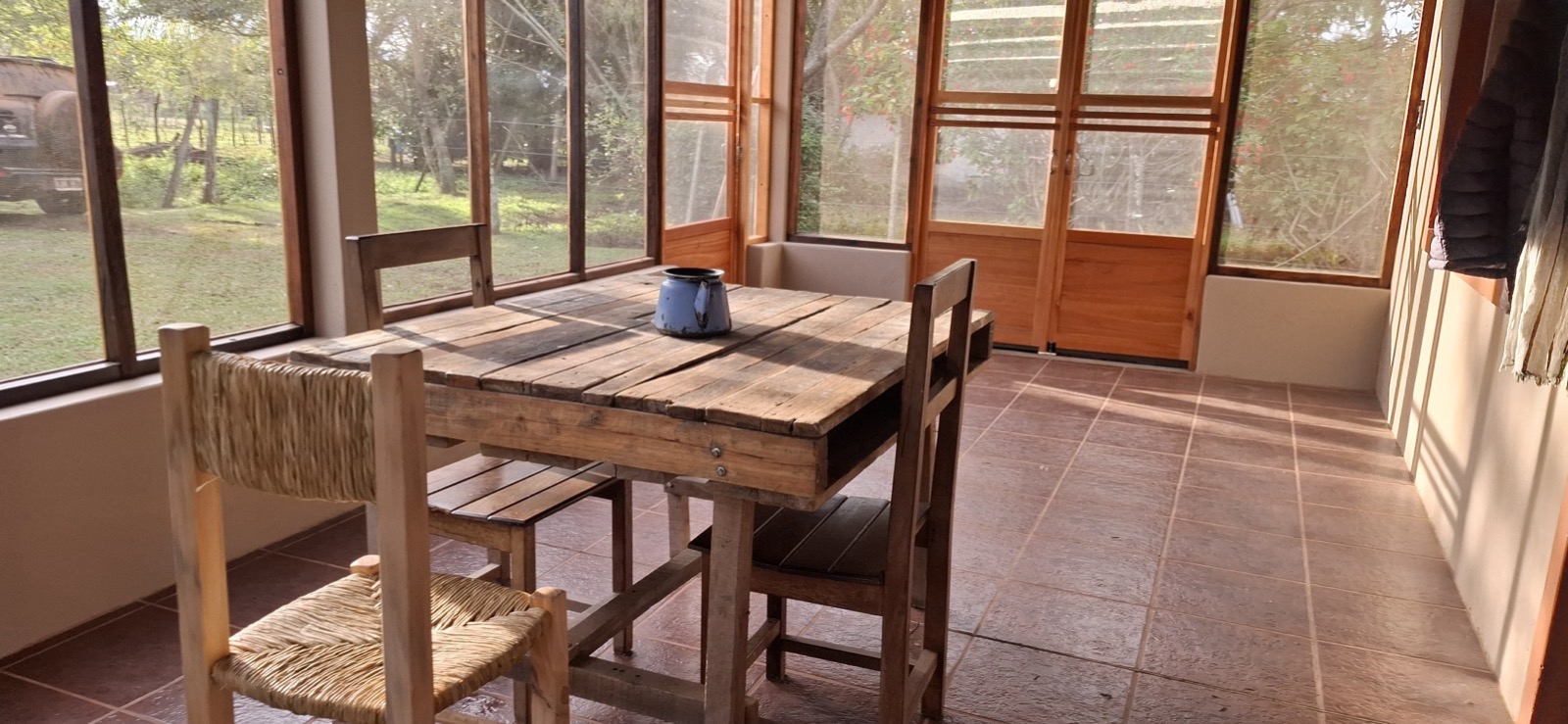 Mesa de madera en el quincho, rodeada de verde