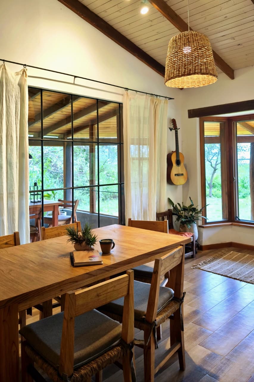 Comedor con mesa de madera, vigas y jardín
