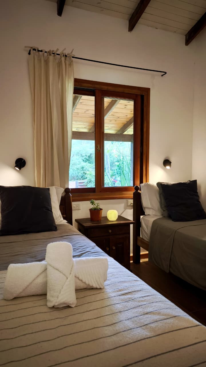 Habitación twin con ventana al jardín y vigas de madera