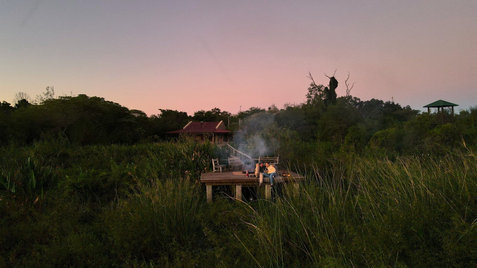 La casa, la pasarela y el deck sobre el estero, vistos desde el aire al atardecer