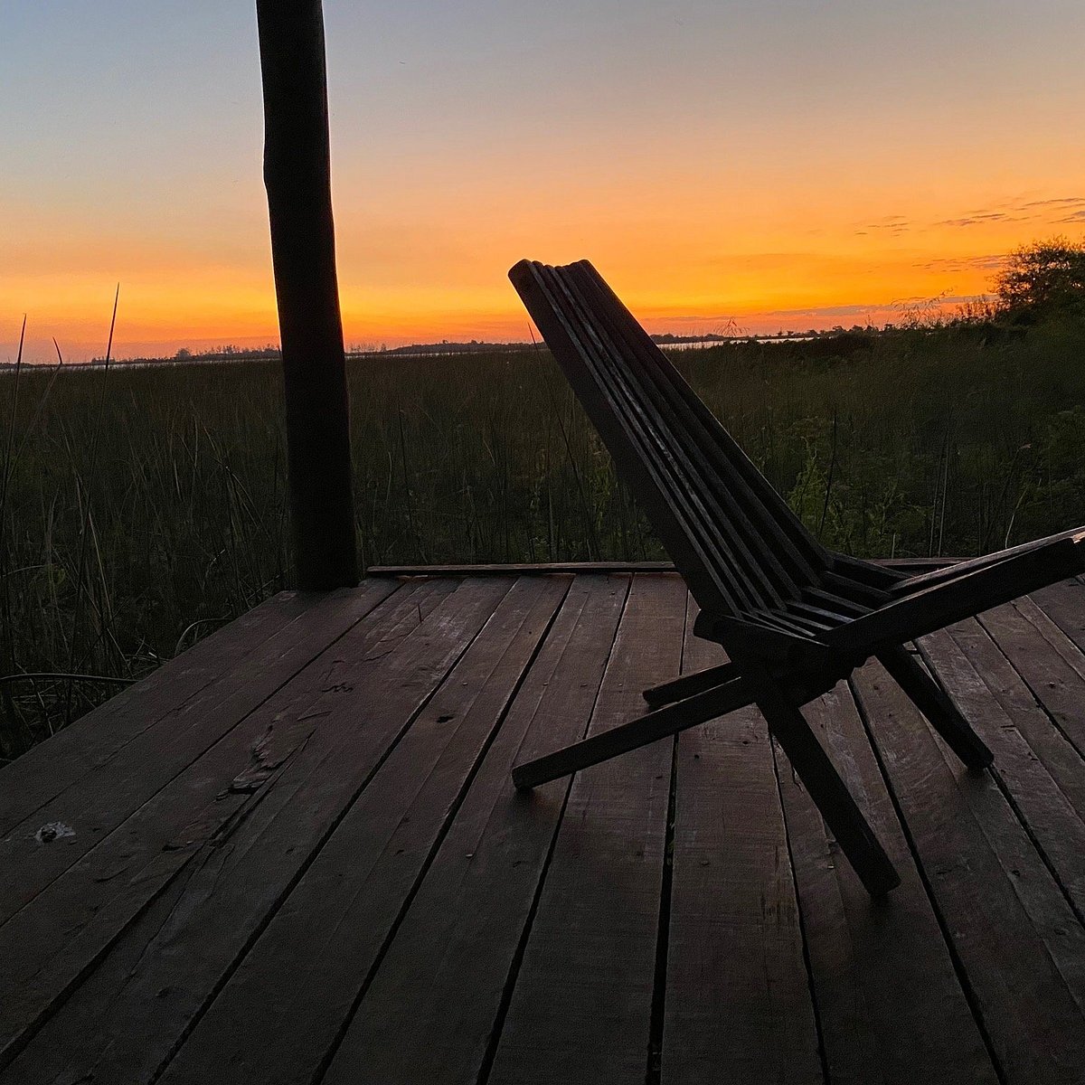 Sillón en la galería con vista al estero al atardecer naranja