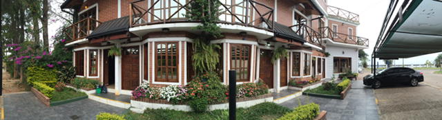 Fachada con galerías de madera y jardín florido