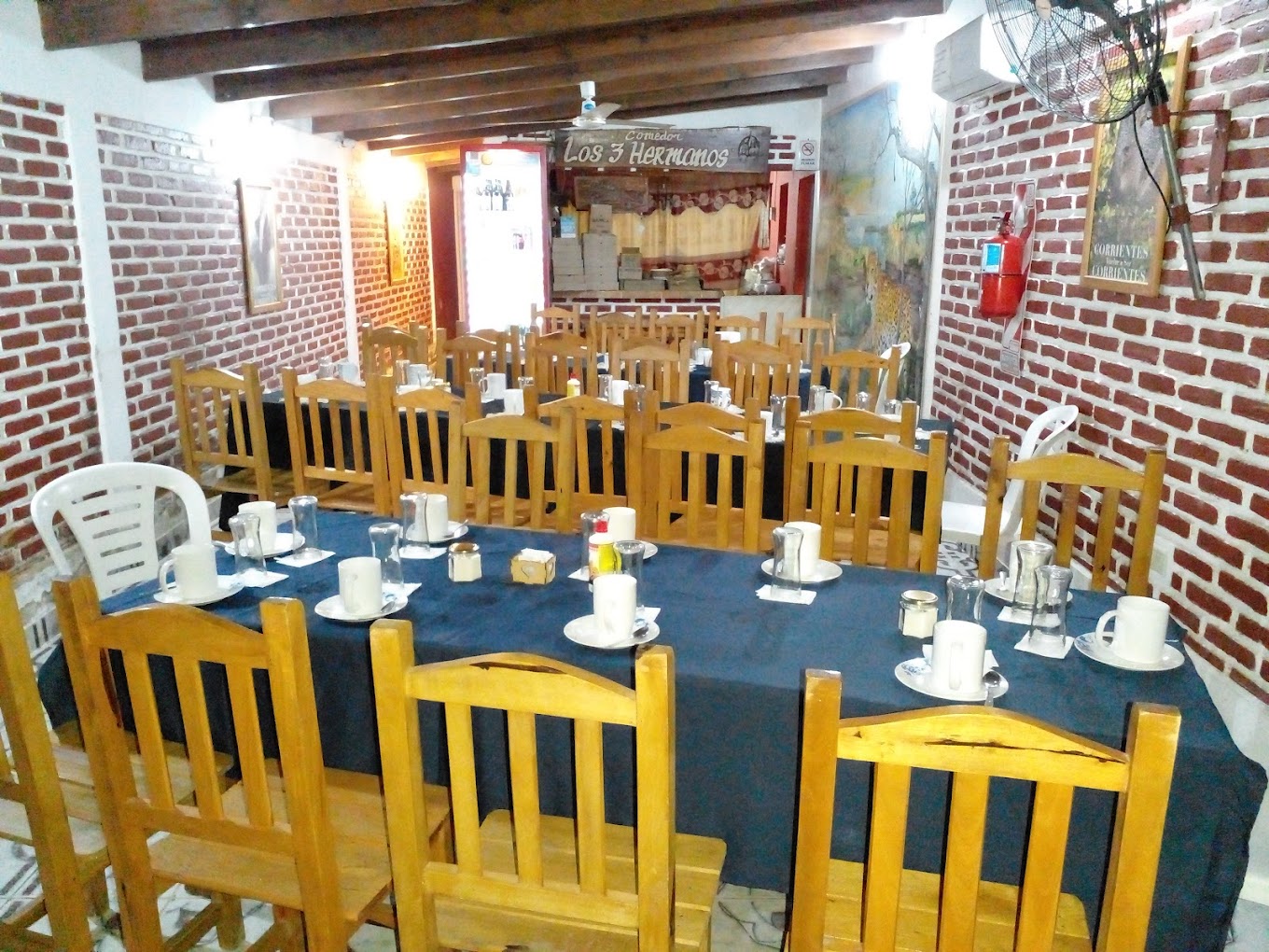 Salón interior con mesas largas y murales del Iberá en Los 3 Hermanos