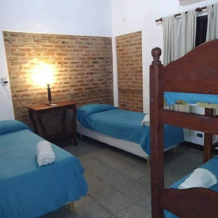 Habitación con camas individuales y pared de ladrillo