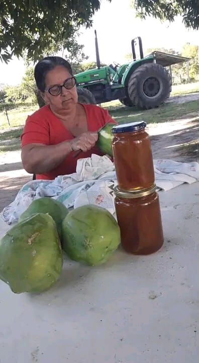 Peeling green papaya for the preserve, next to the filled jars