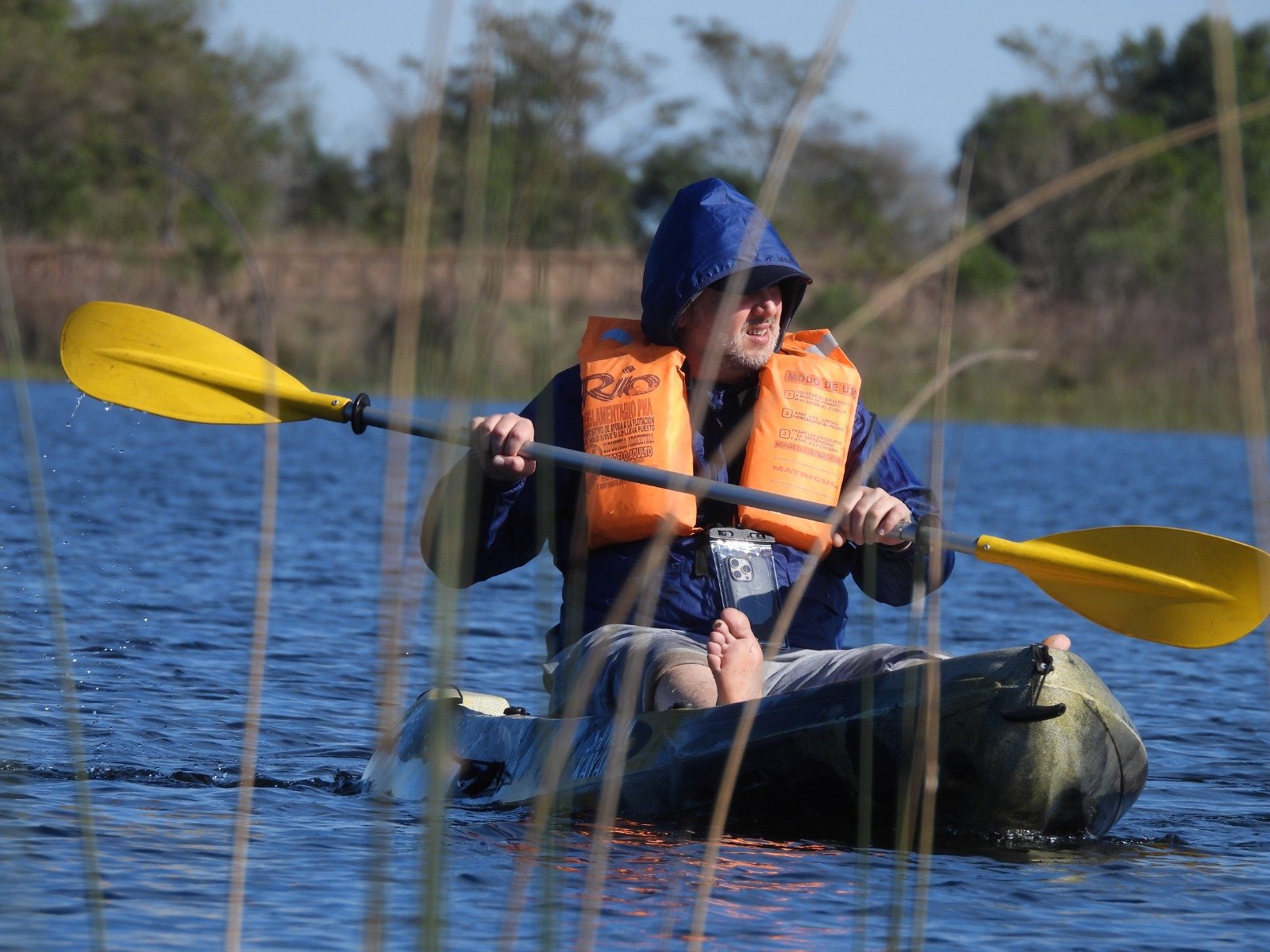 Remando en kayak, con chaleco y campera de lluvia