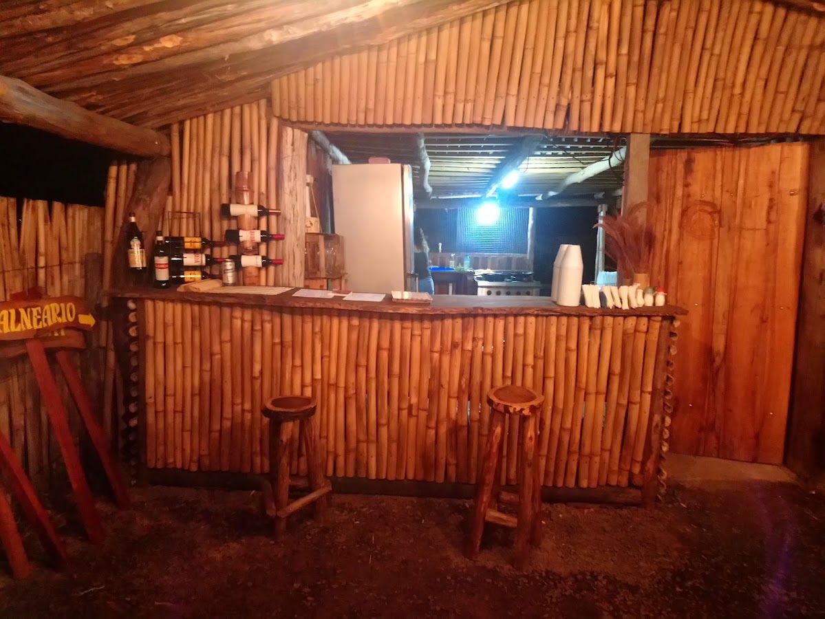 Barra de bambú con vinos y rones, taburetes de madera al anochecer