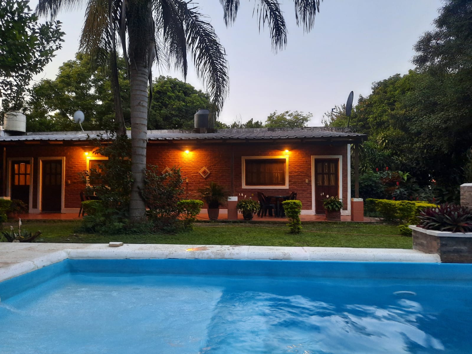 La galería de ladrillo visto y el jardín, al atardecer