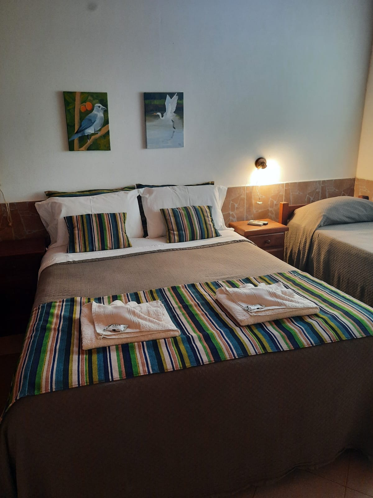 Habitación con cama matrimonial y cuadros de aves del Iberá