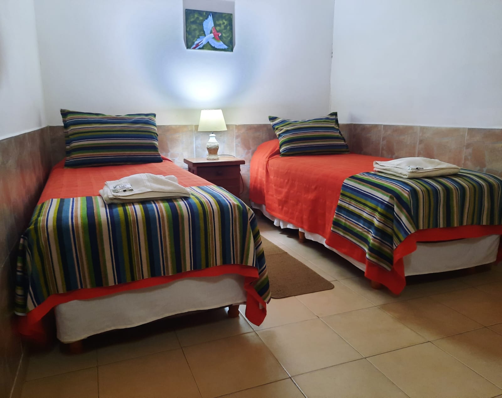 Habitación con dos camas y un cuadro de guacamayo