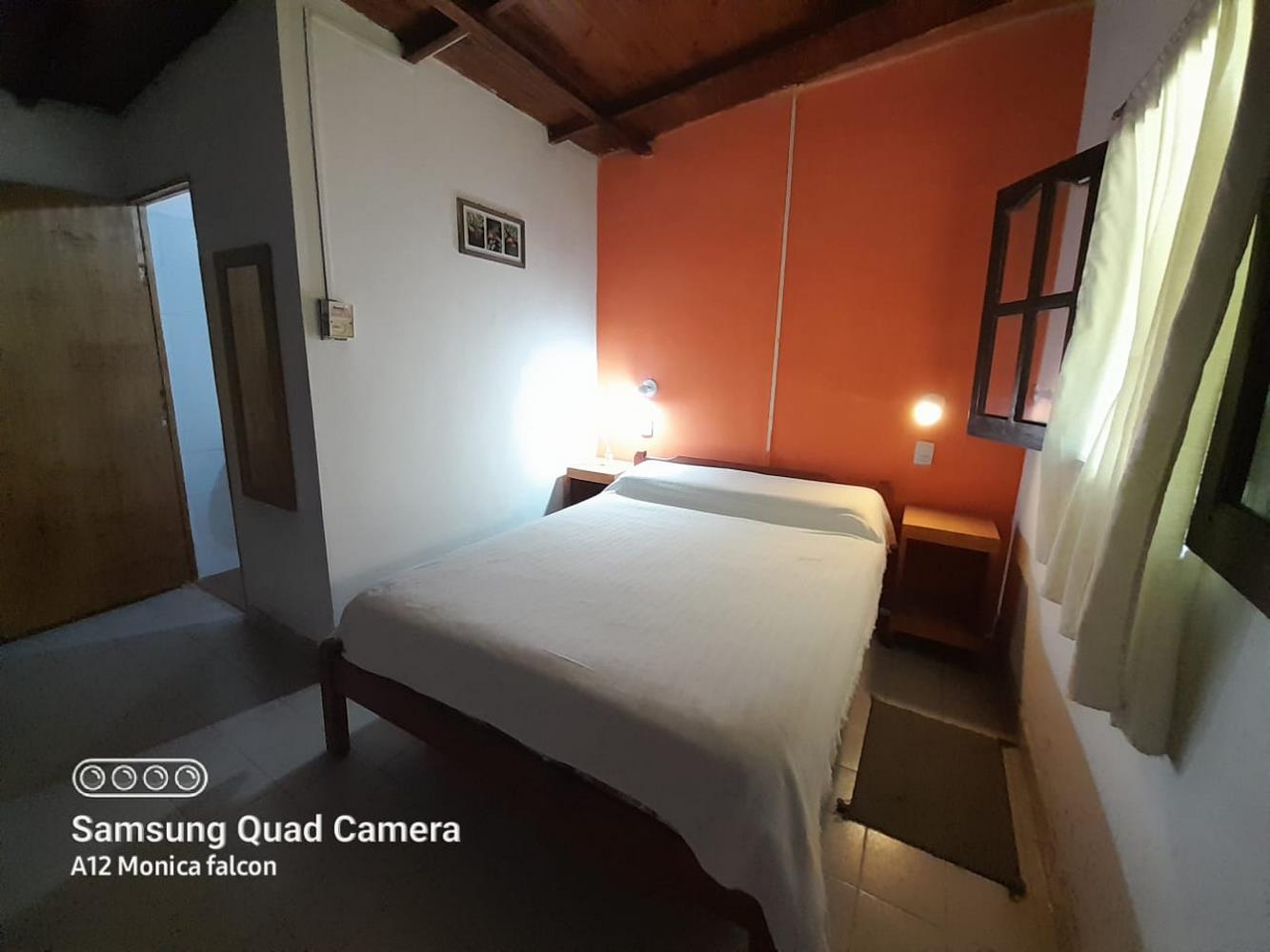 Habitación doble con pared naranja y vigas de madera