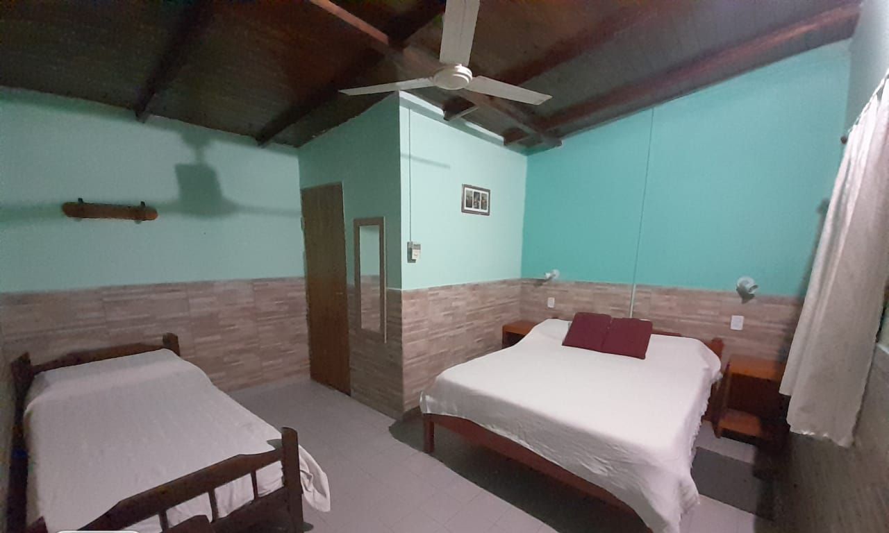 Habitación triple con pared turquesa y ventilador de techo