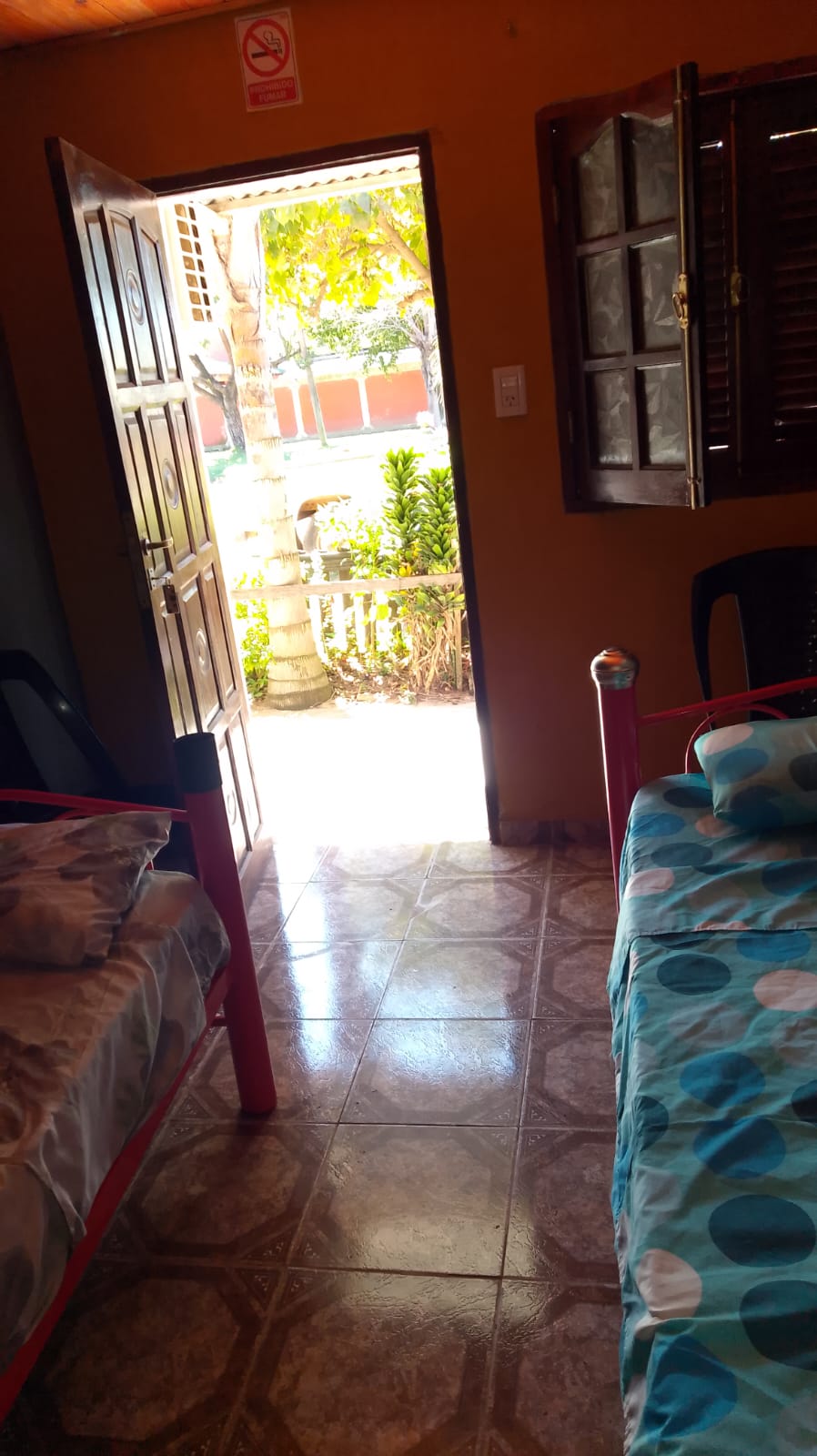 Una habitación con dos camas, con la puerta abierta al patio