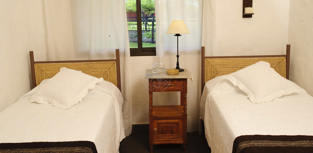 Habitación twin con cabeceras de mimbre y vista al jardín