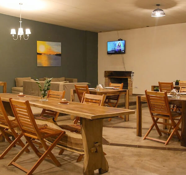 Salón comedor con mesas de madera y chimenea  -  ambiente acogedor
