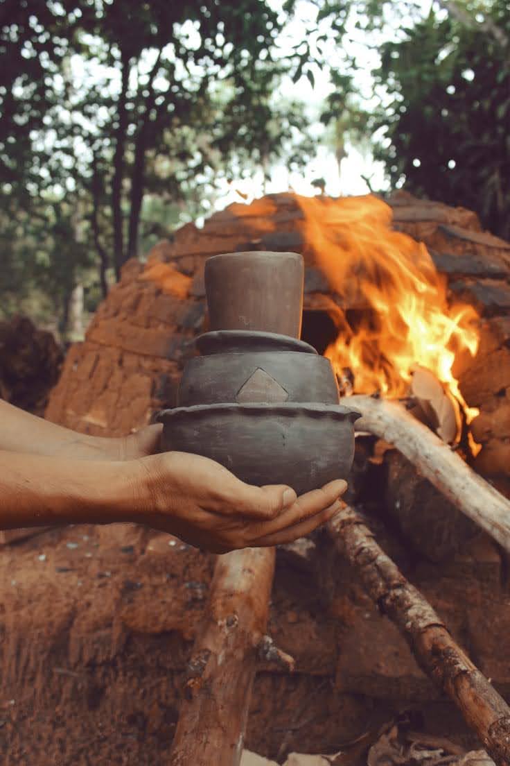 A ceramic pot in front of the lit clay oven