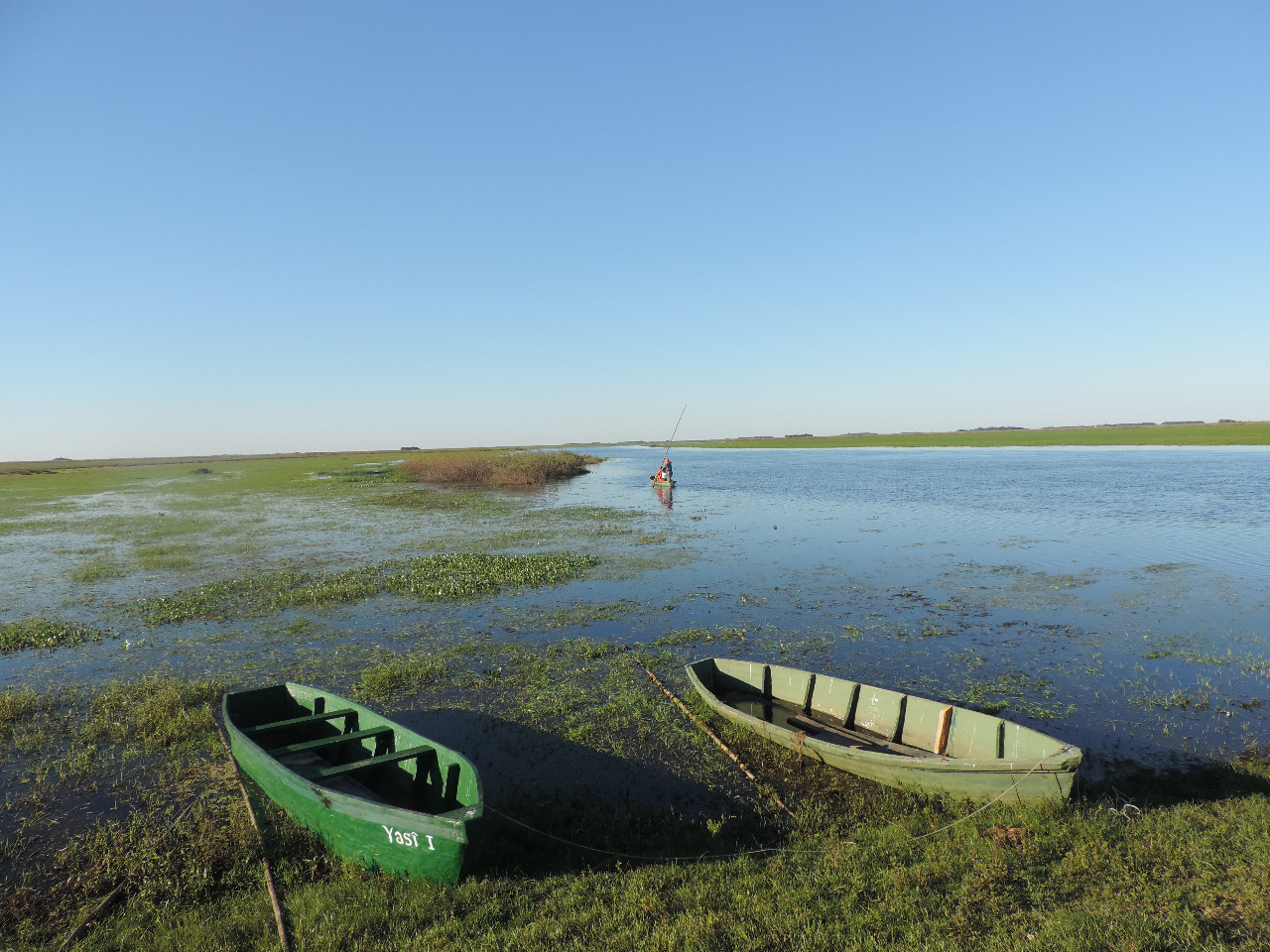 Canoas en la orilla y pescador solitario en el espejo de agua del Iberá