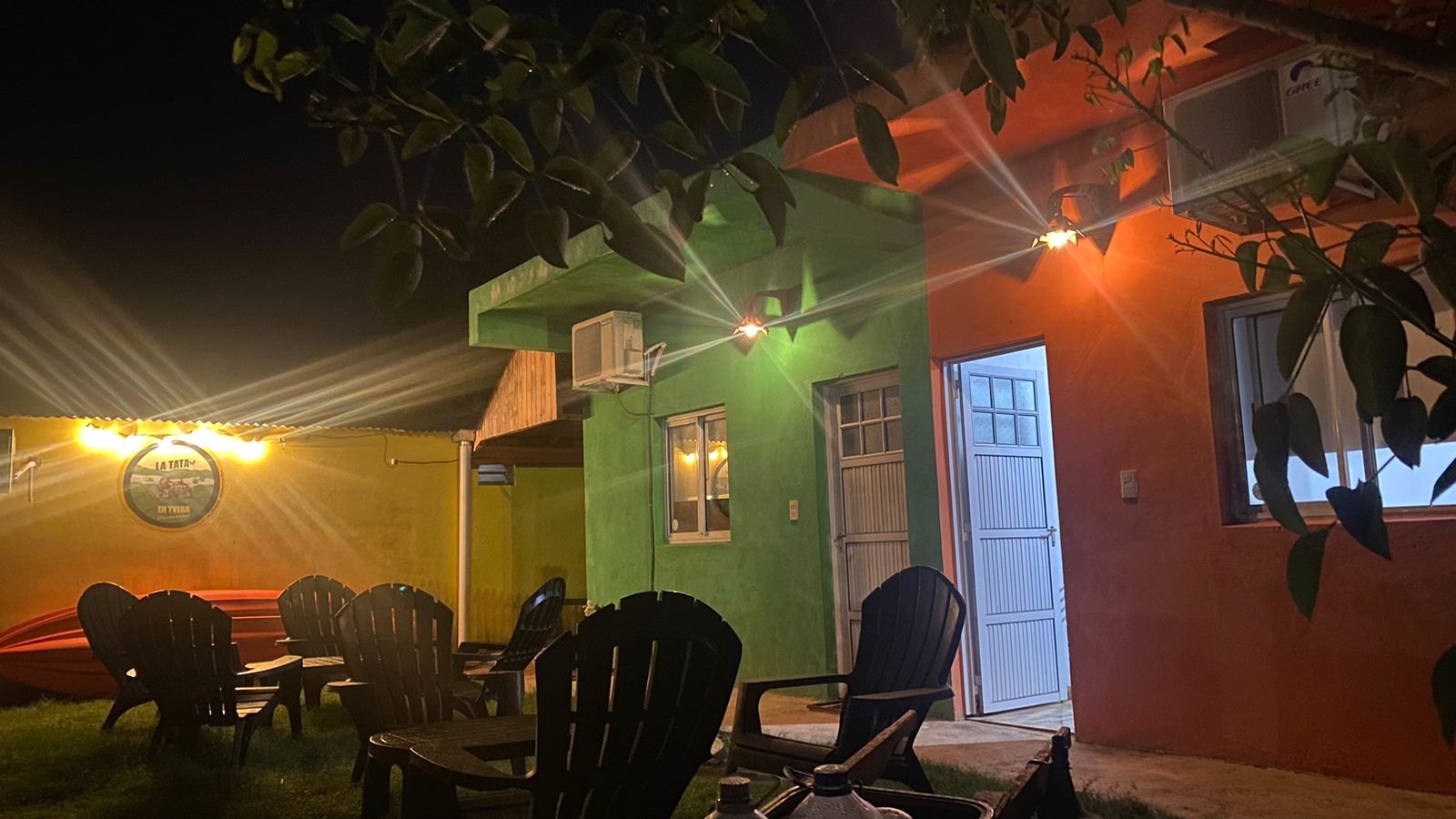 La casa iluminada de noche, con el jardín y las reposeras
