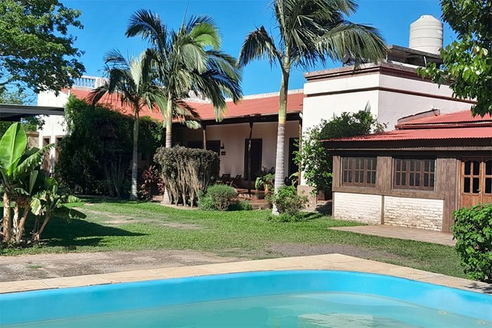 Pileta rodeada de jardín, con la posada de fondo