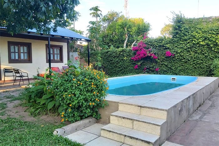 Pileta con buganvilla florecida y jardín alrededor