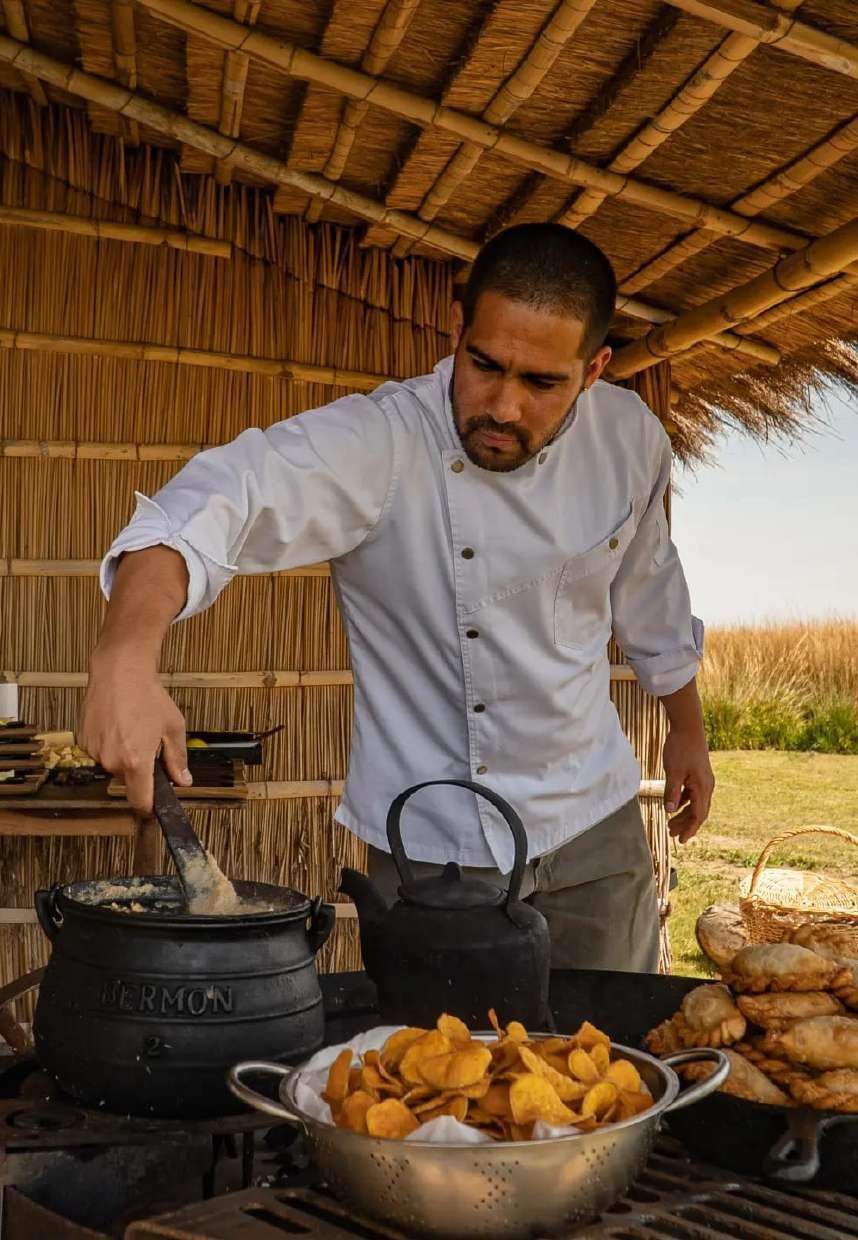 El cocinero revolviendo la olla de hierro bajo el techo de paja
