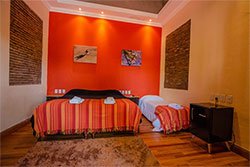 Habitación twin con pared naranja y piso de madera