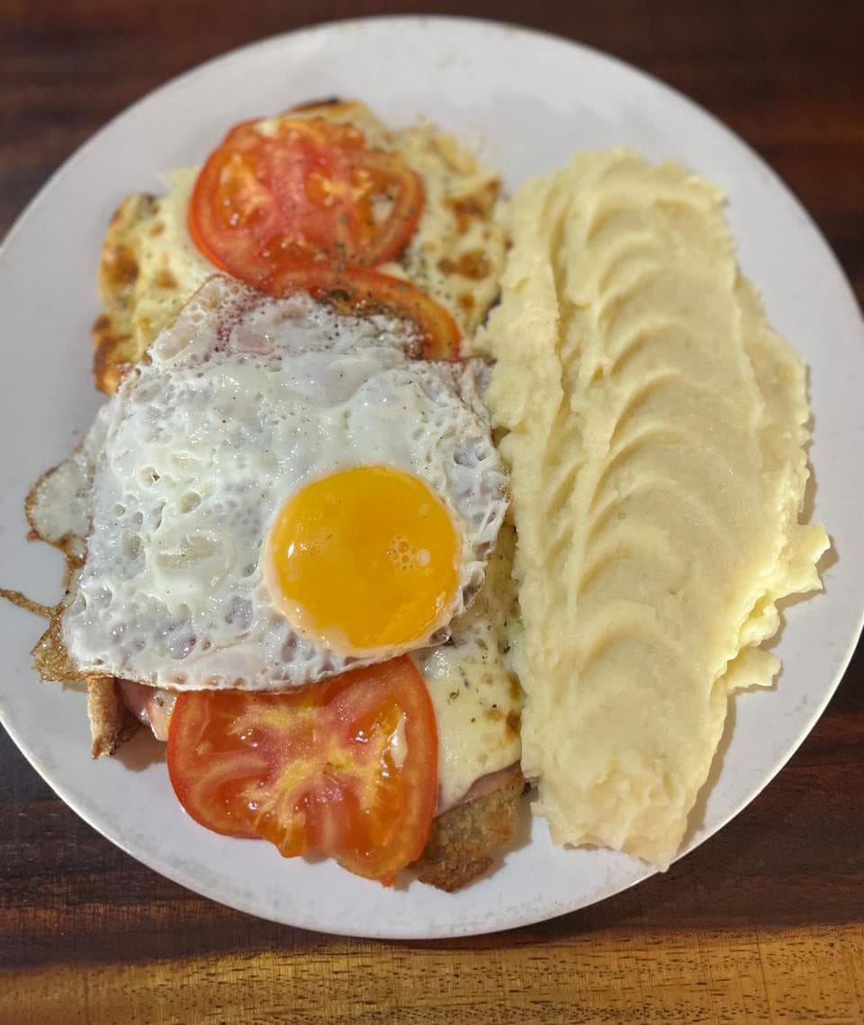 Breaded cutlet topped with a fried egg, with mashed potatoes