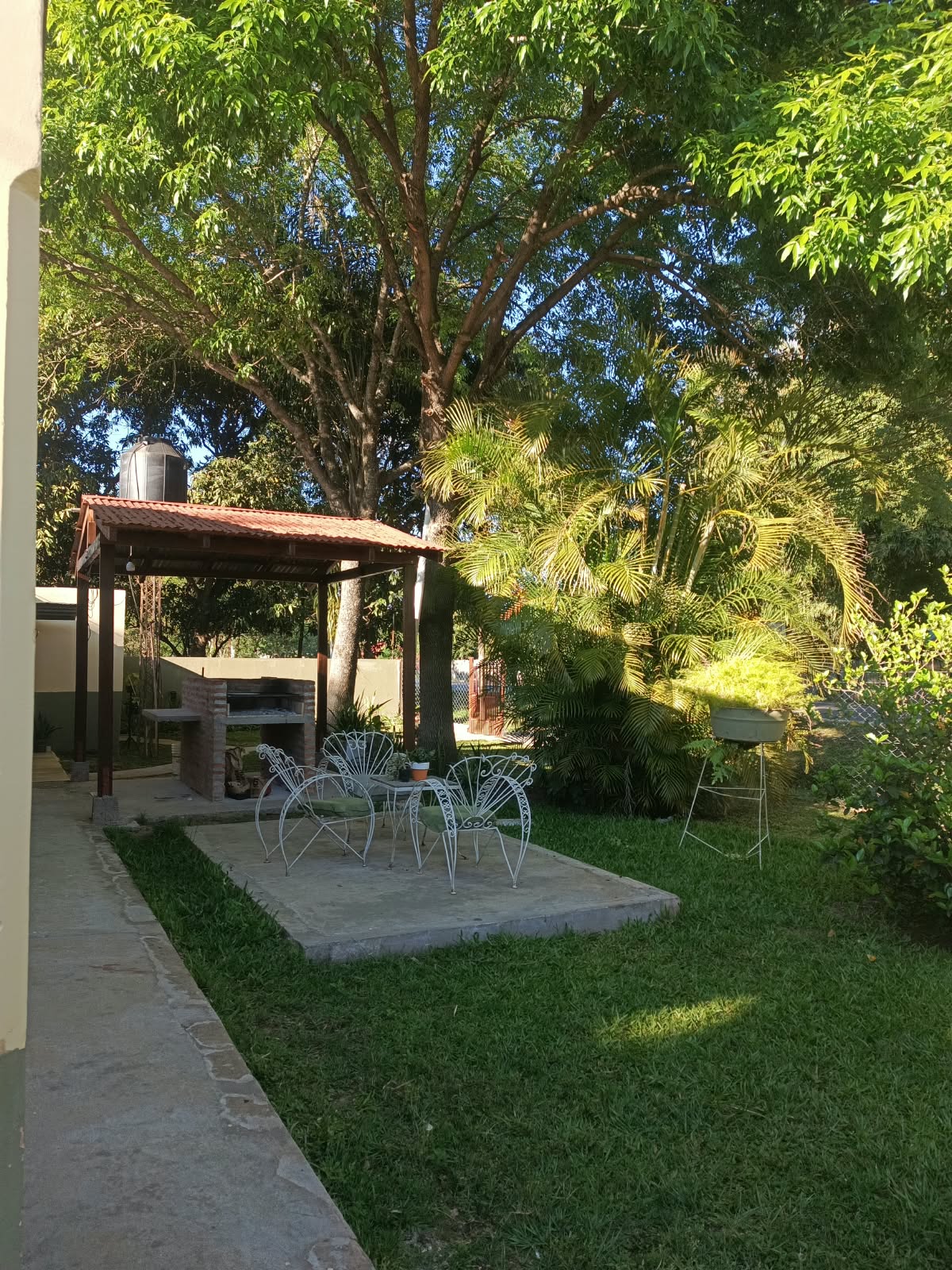 The garden, with the iron armchairs and the covered grill