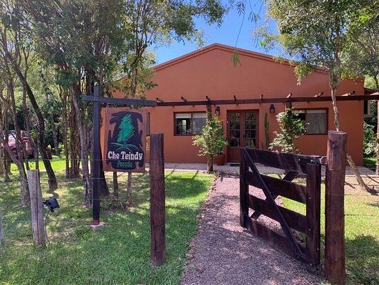 Entrada con cartel de madera y jardín nativo