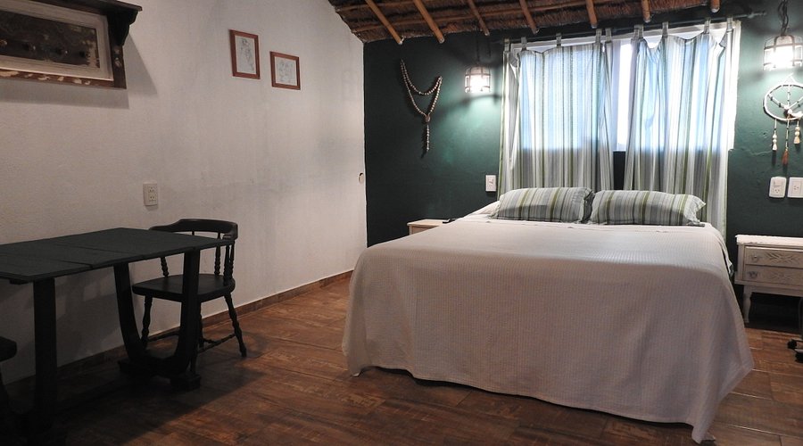 Habitación con cama doble, techo de cañas y paredes terracota