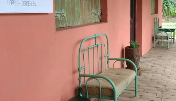 Galería exterior con sillones de hierro forjado y patio de ladrillo
