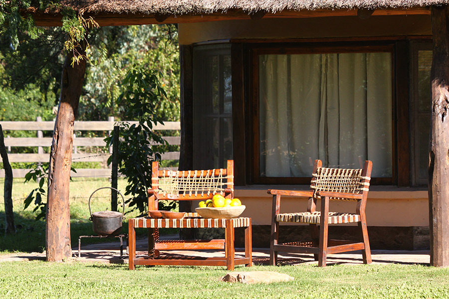 Galería con sillones tejidos frente a la cabaña  -  jardín del rancho