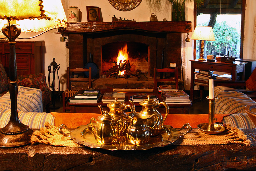 Sala con chimenea encendida y servicio de té en pava de plata