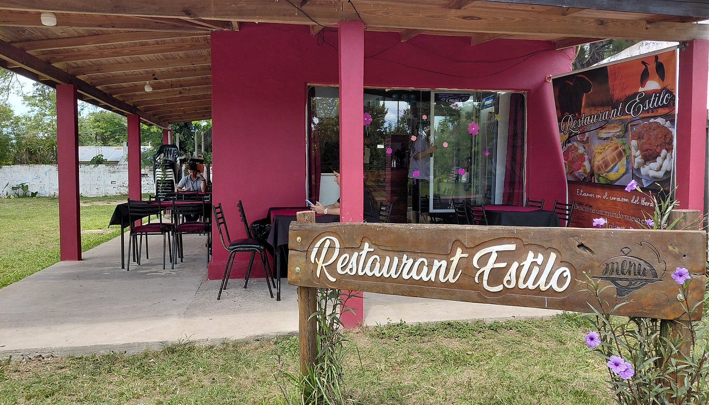 Galería exterior del Restaurant Estilo con mesas y cartel de madera