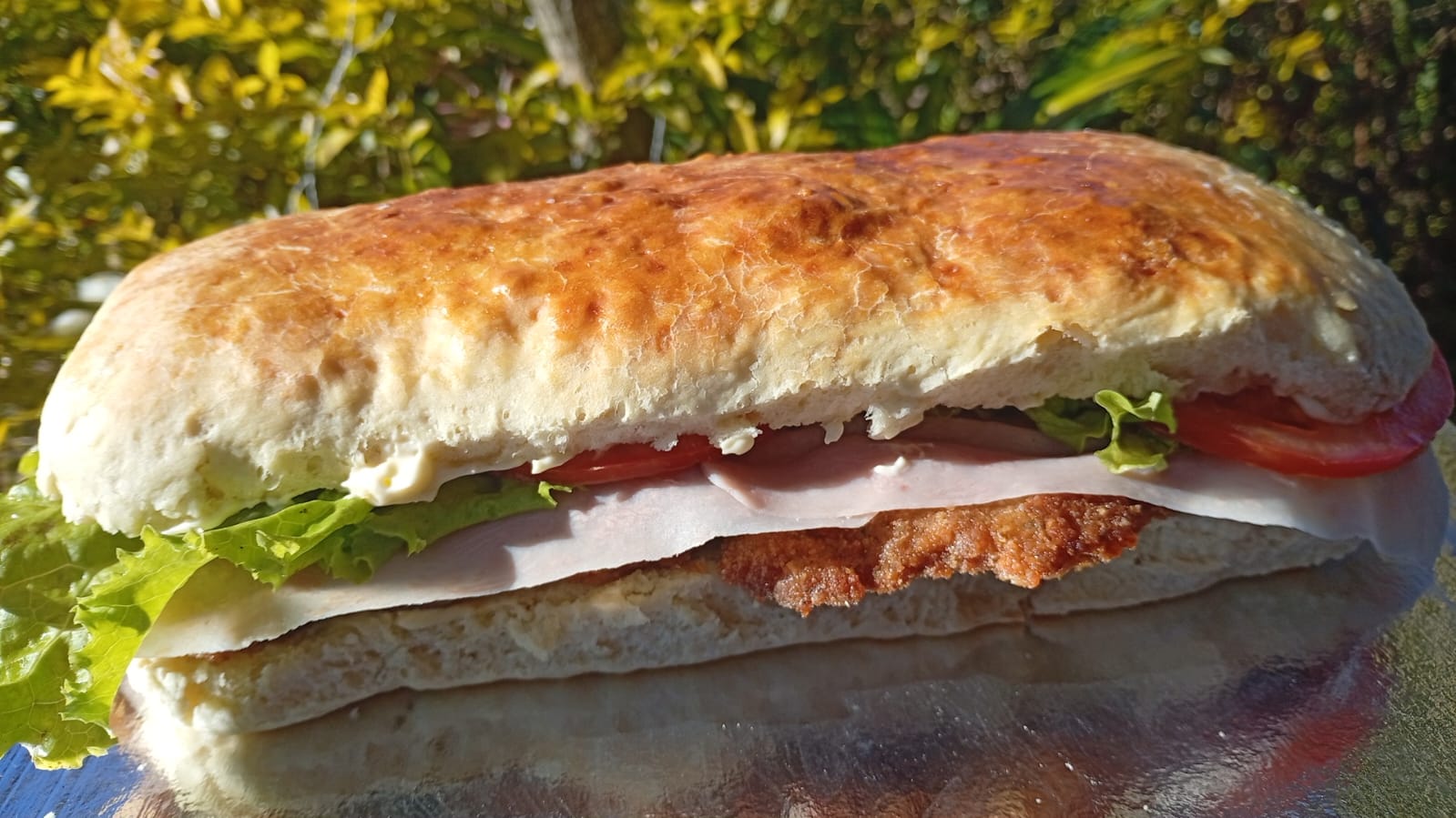 Sándwich de milanesa con jamón, lechuga y tomate