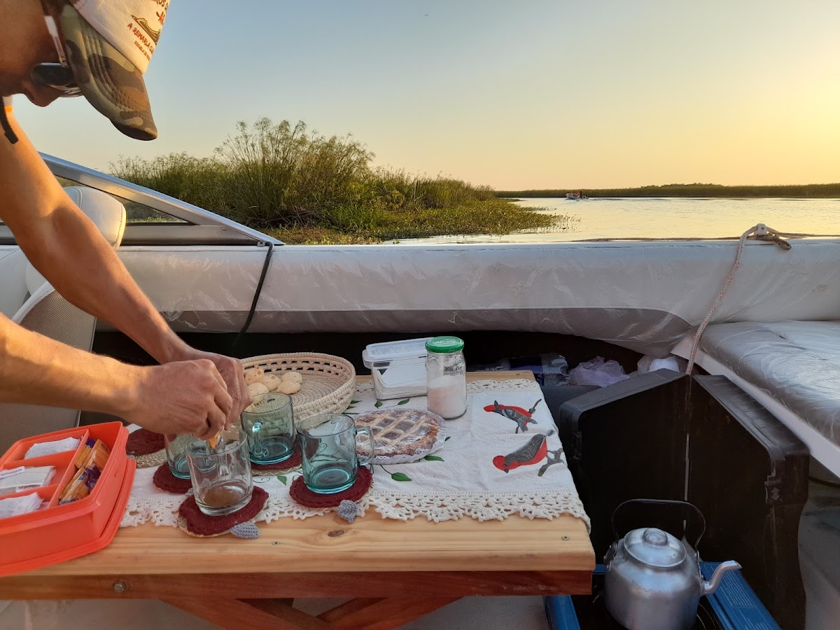 Guía preparando mate a bordo al atardecer entre los camalotes del Iberá