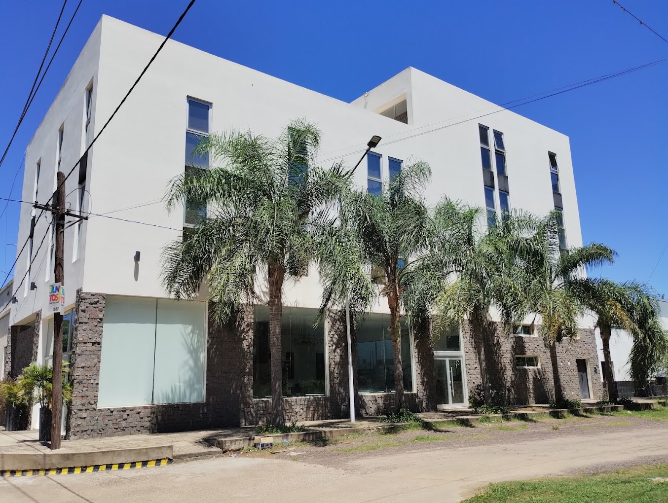 Edificio del Tobuna Suites con palmeras bajo cielo azul