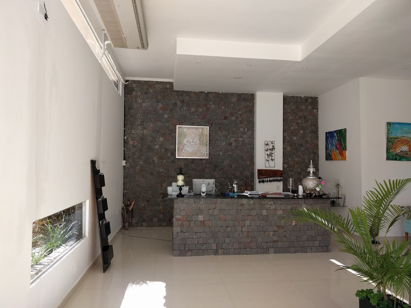 Recepción del Tobuna Suites con pared de piedra y pinturas de fauna del Iberá