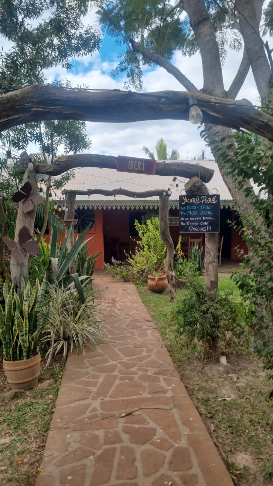 Entrada al restaurante por el sendero de piedra, entre plantas y madera