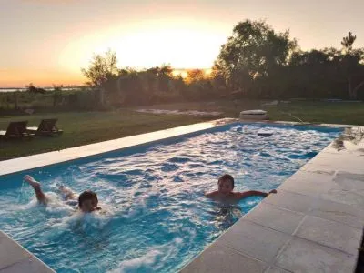 Piscina al atardecer con bañistas y vista a los esteros