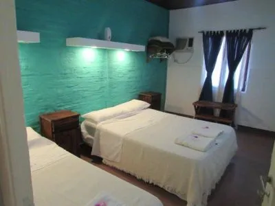 Habitación triple con pared turquesa y camas individuales