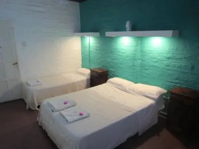 Habitación doble con pared turquesa y camas vestidas